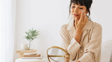 Woman in beige pajamas applying face moisturizer