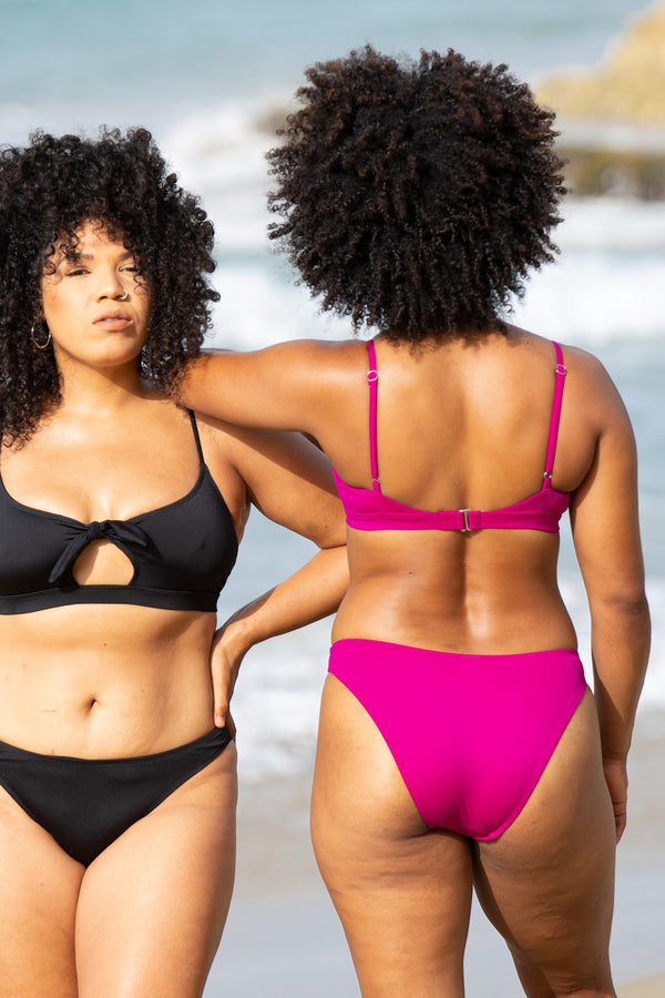 Kailini Bikini Bottom in raspberry, back view on model on beach showing high cut leg and clean edges.