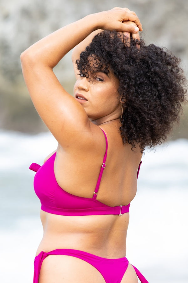 Marina Bralette in raspberry, back view of model on beach showing back hook closure.
