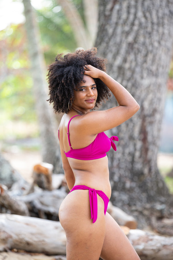 Woman in thong bikini bottom, raspberry color, side view