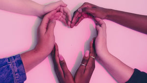 A group of women's hands forming a heart shape.