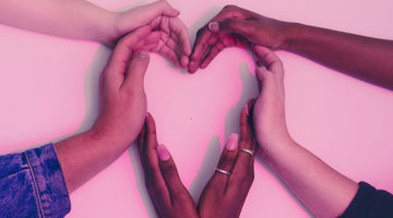 A group of women's hands forming a heart shape.