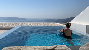 Woman in pool overlooking ocean in Santorini Greece