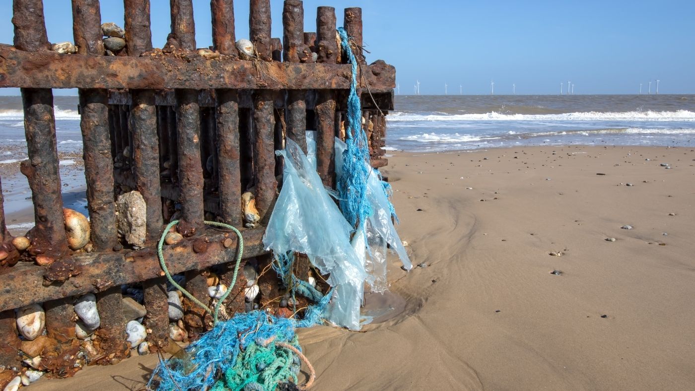 Fence on beach with plastic bags hanging off side