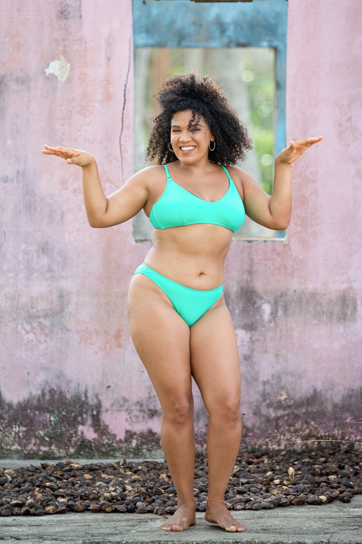 Kailini Bikini Bottom in green, front view on model standing in front of colorful wall, showing high cut leg and clean lines.