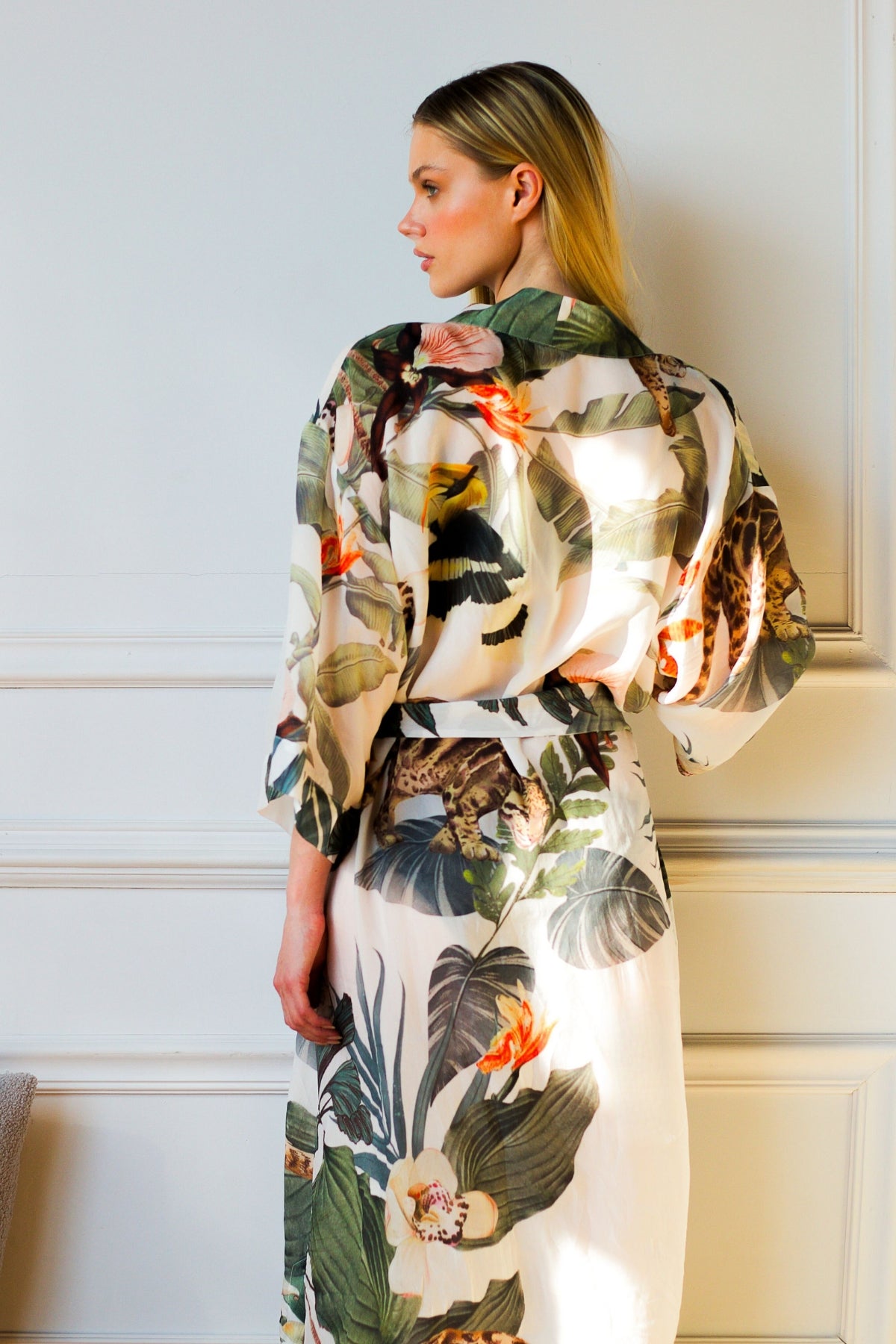 Model wearing Bambina Swim Cardamom robe in tropical print, back view highlighting belt and dropped shoulder and relaxed sleeves.