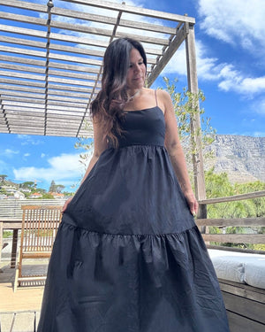 Woman in a black dress standing outdoors with a scenic background