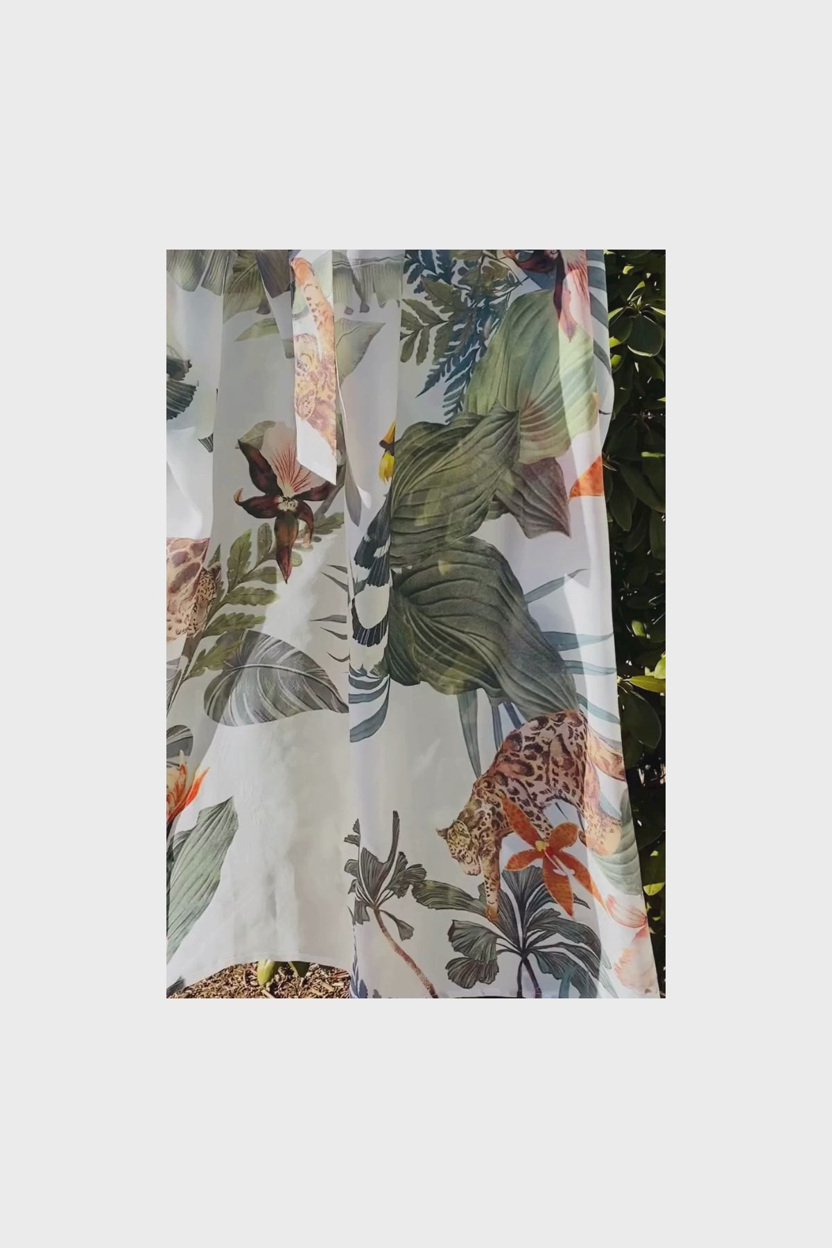 Close-up video of Bambina Swim Cardamom robe fabric in tropical print moving in breeze showing texture and color detail.