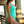 Load image into Gallery viewer, Side view of woman standing under beach pier wearing a green one piece swimsuit.
