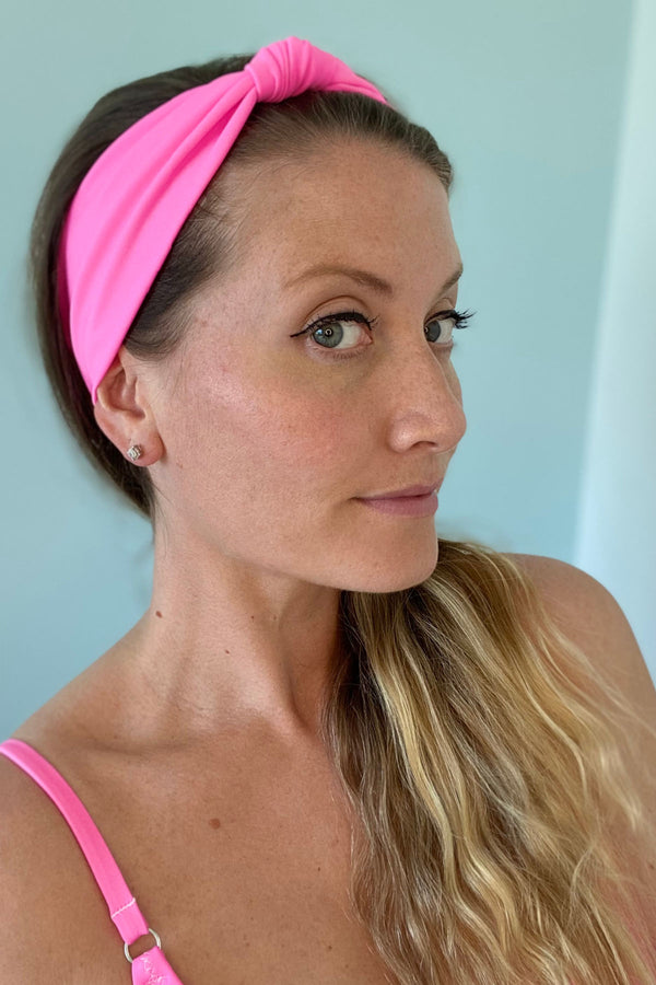 Woman wearing pink headband with knot on top.